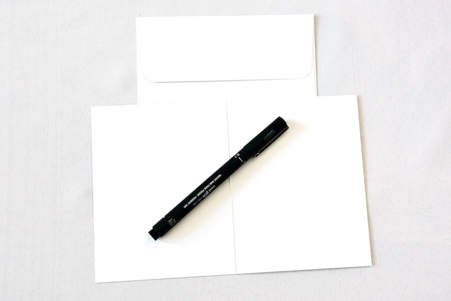 Card open showing blank inside with white envelope and pen