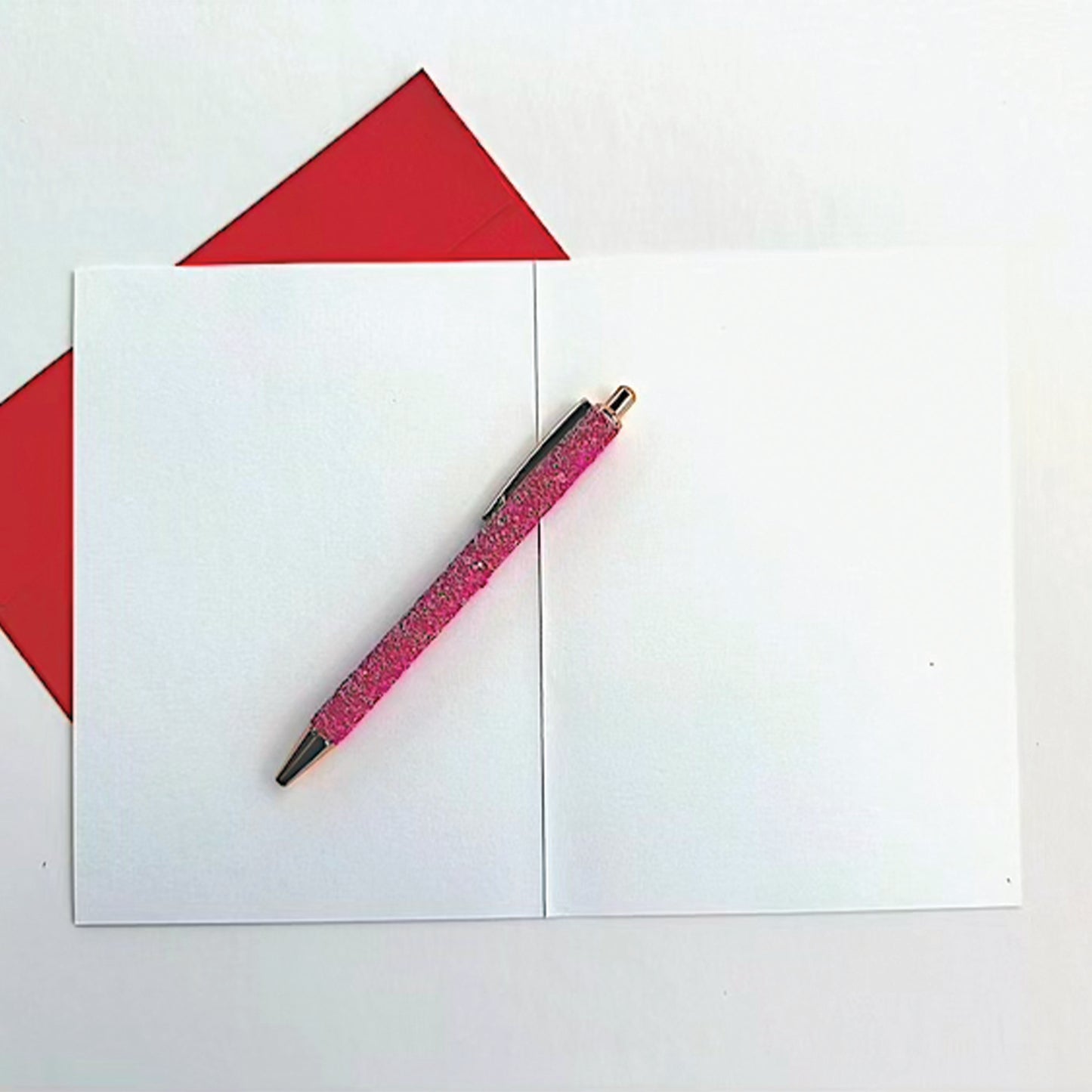 Holiday card open showing blank inside with red envelope and glitter pen