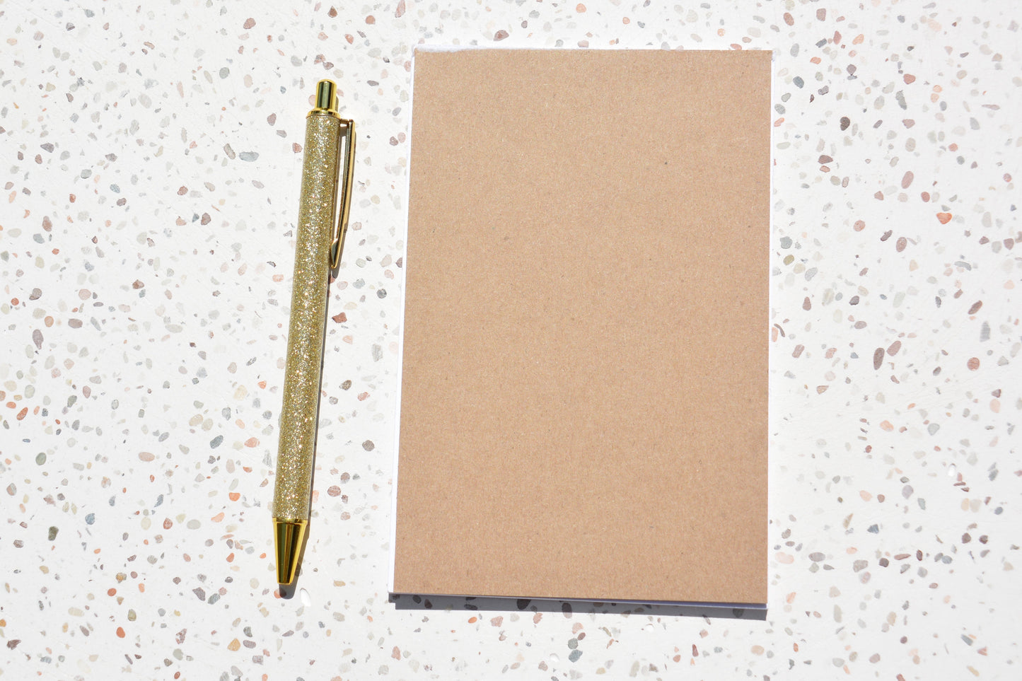 Back of jellyfish notepad with a gold pen on a speckled surface