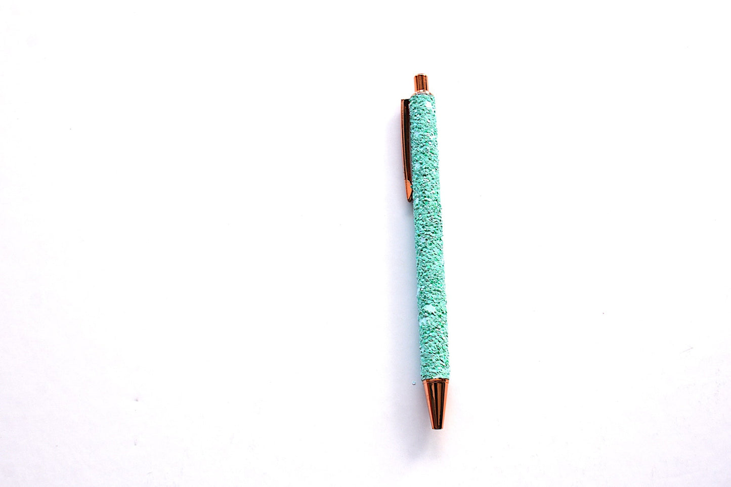 Glitter pen in aqua color with sequined sparkly texture with rose gold accents on white background