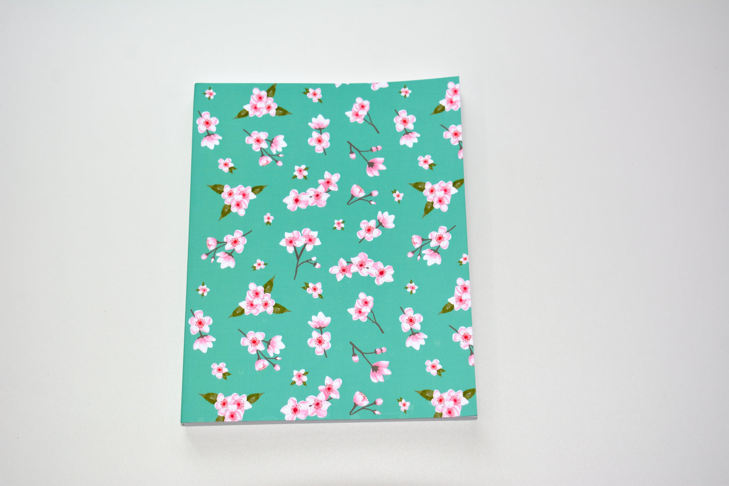 Cherry blossom Floral-patterned notebook  with pink flowers, green leaves on an aqu background