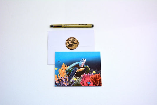 Notecard with painted turtle swimming underwater with coral and fish with white envelope and pen