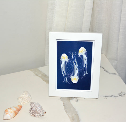 jellyfish art print framed in white wood with glass displayed on marble table with seashells