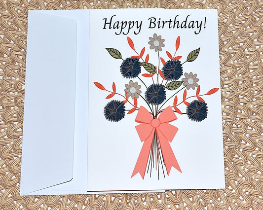 Birthday card with floral design and pink bow with white envelope placed on a textured surface