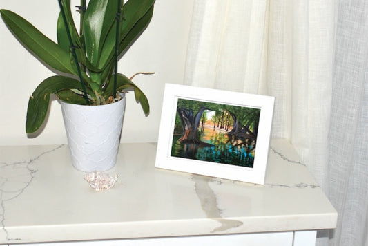 Framed Art Print displayed on nightstand with plant and seashell