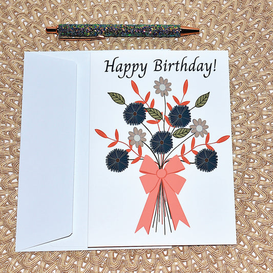 Birthday card with floral bouquet and big pink  bow with white envelope and glitter pen on a textured surface