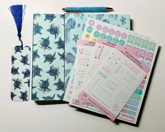 Stationery set with notebook, planner stickers, a bookmark and a glitter pen on a light background