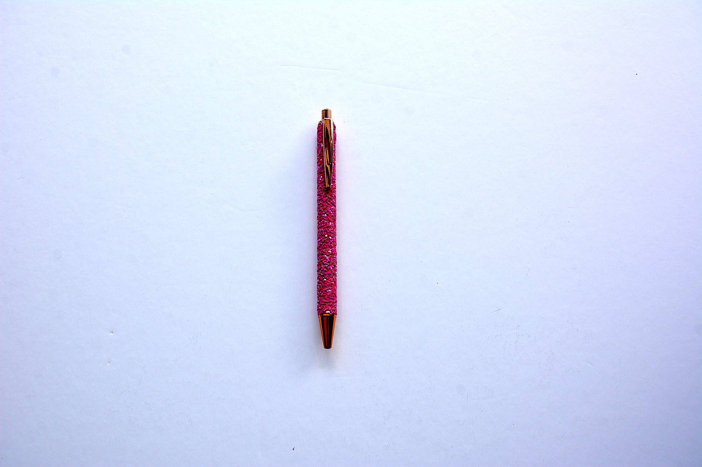 Glitter pen in magenta color with sequined sparkly texture with rose gold accents on white background