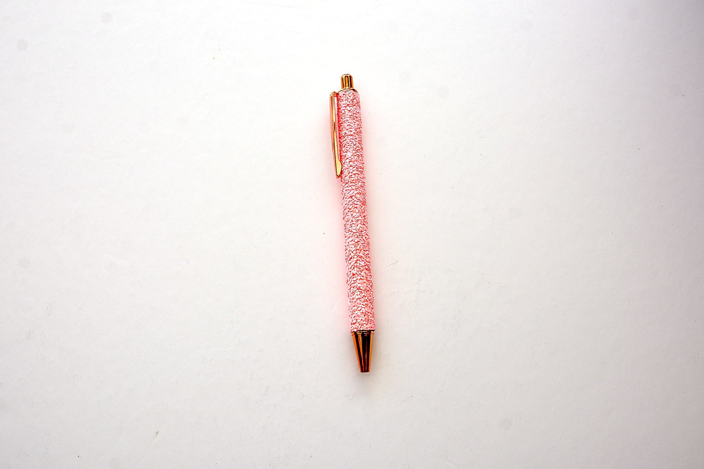 Glitter pen in pink color with sequined sparkly texture with rose gold accents on white background