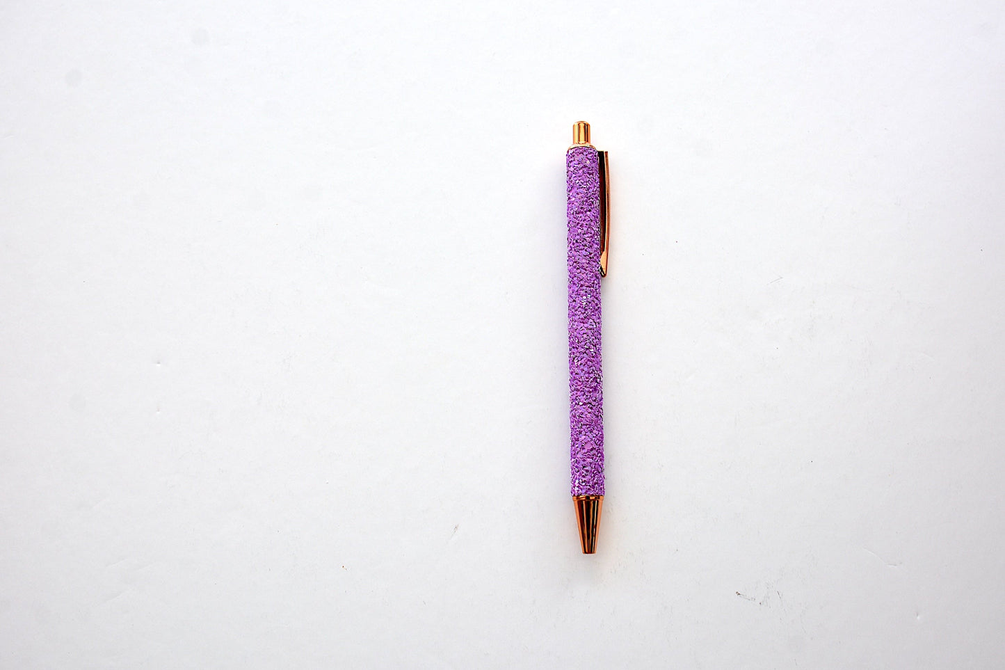 Glitter pen in purple color with sequined sparkly texture with rose gold accents on white background