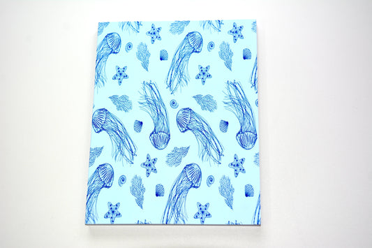 Notebook with pattern of navy blue jellyfish, seashells, sea kelp, and starfish on a light blue background