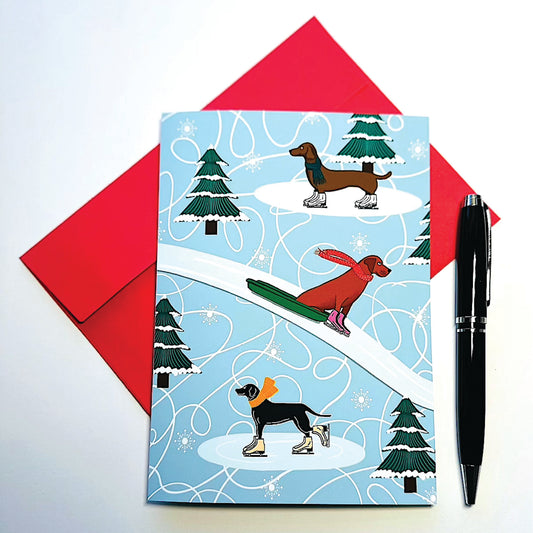 Holiday card with winter-themed illustration of dogs ice skating and on sled with scarves and a red envelope and pen on a white background.